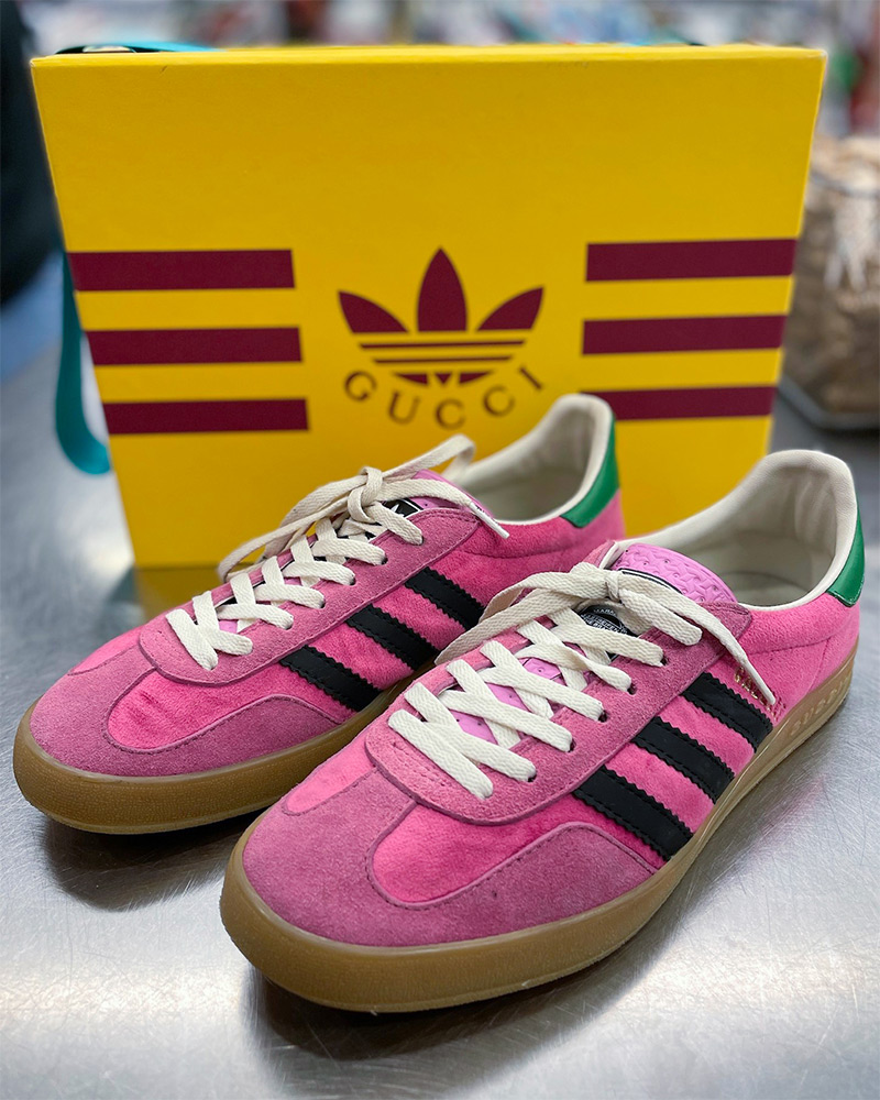 Gucci x Adidas pink sneakers sit on top of a silver counter