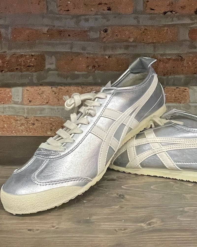 Silver Onitsuka Tiger sneakers against a brick wall