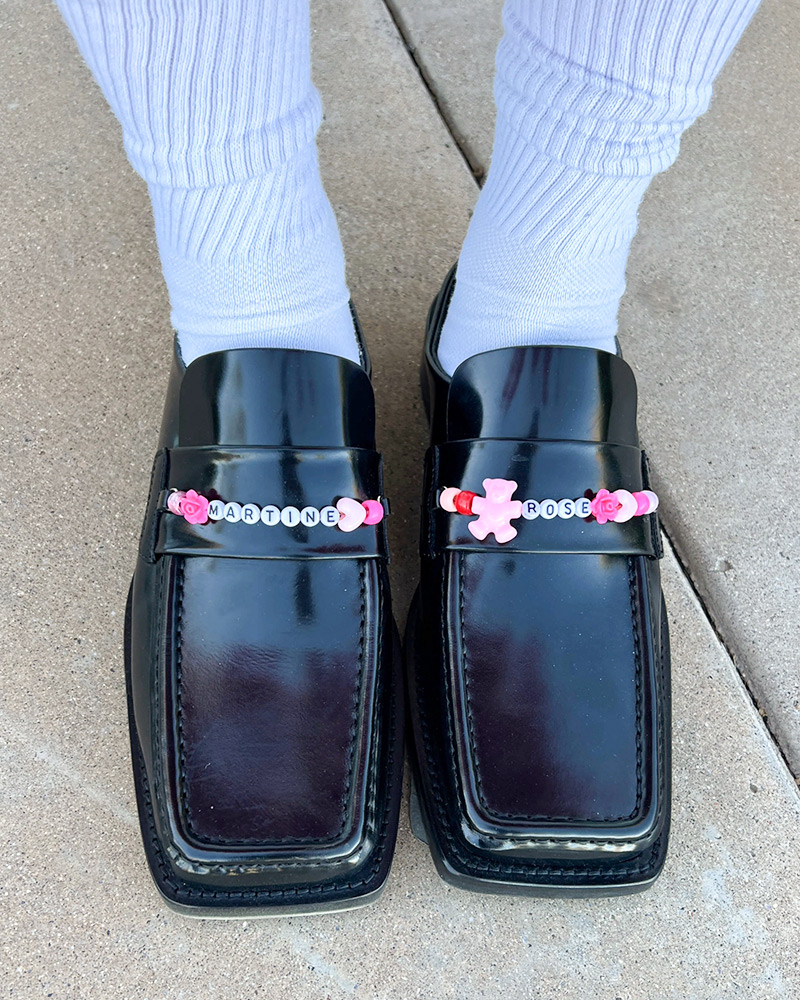 Patent leather loafers with decorated with white and pink beads that spell "Martine Rose"