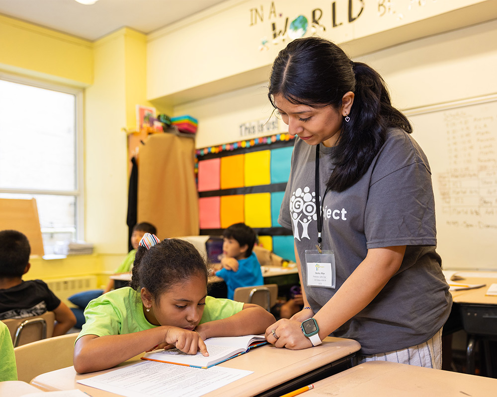 Go Project member teaching student at desk