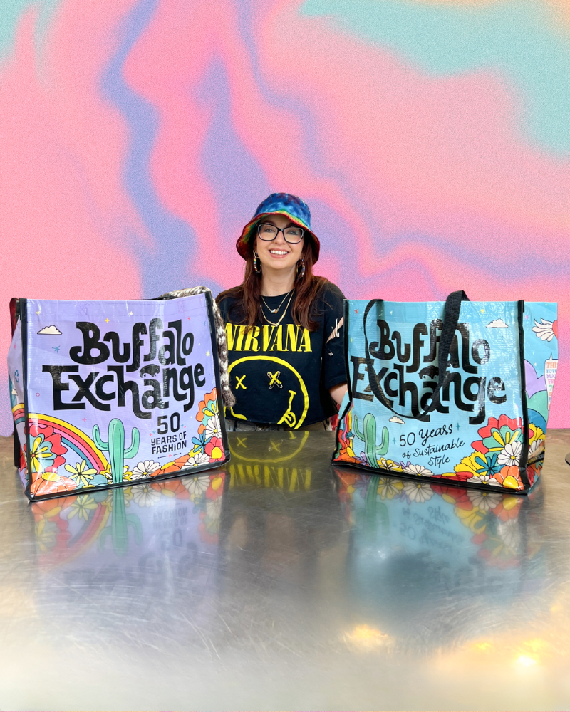A Buyer stands behind a counter with two Buffalo Exchange totes on either side of them