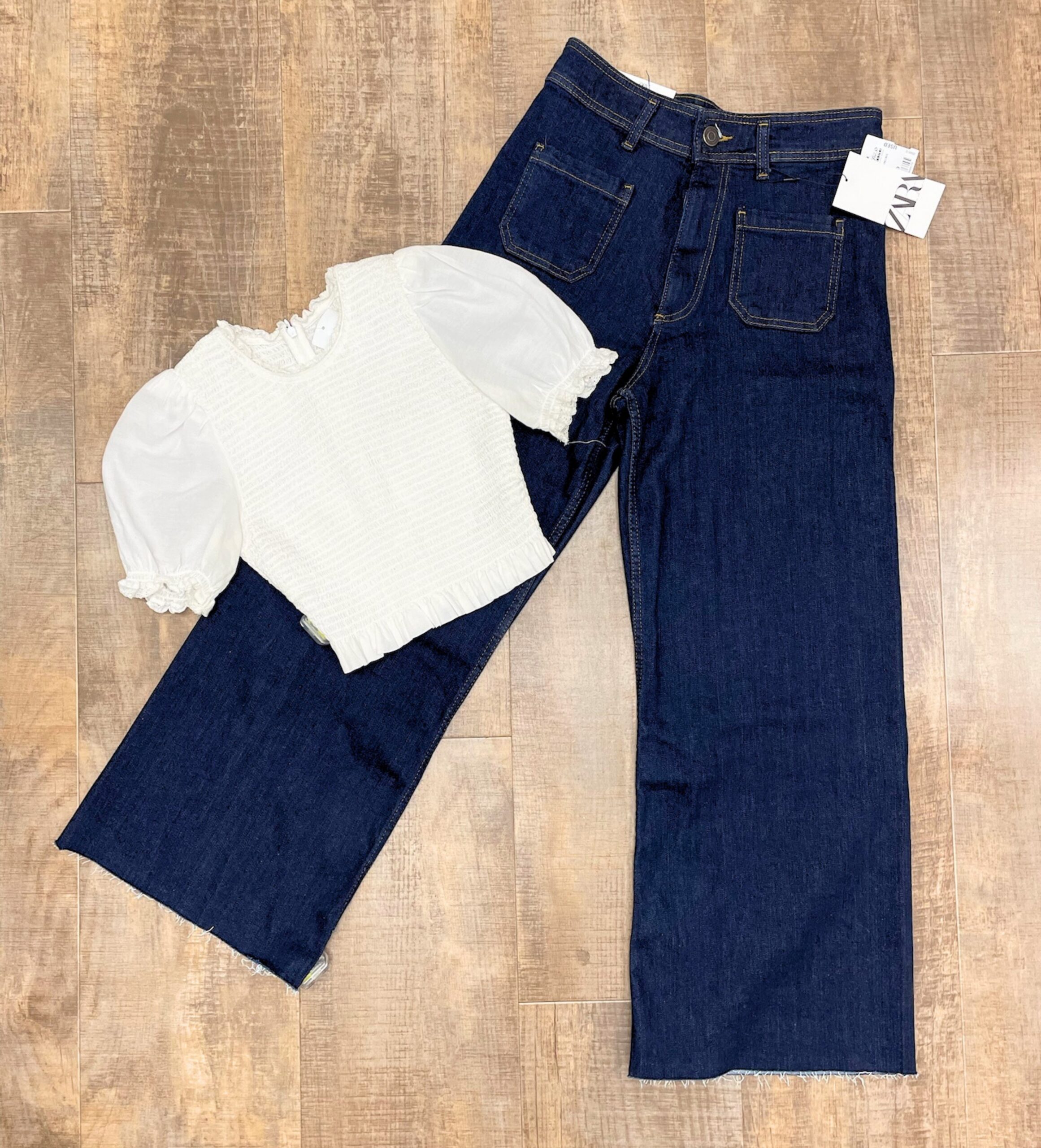 Flat lay of wide-leg zara denim and cream puff sleeve crop top blouse
