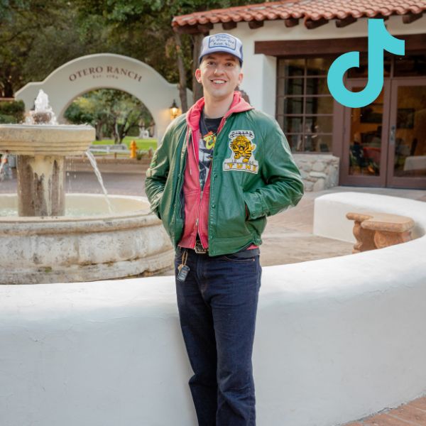 person standing in jeans and green vintage jacket with tiktok logo overlay