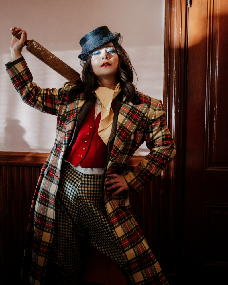 Singer songwriter Mitski wearing a plaid coat holding a rolling pin